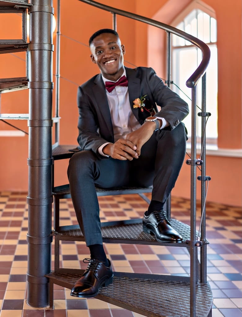 Bernard Sarfo Twumasi on a spiral staircase, seated and smiling